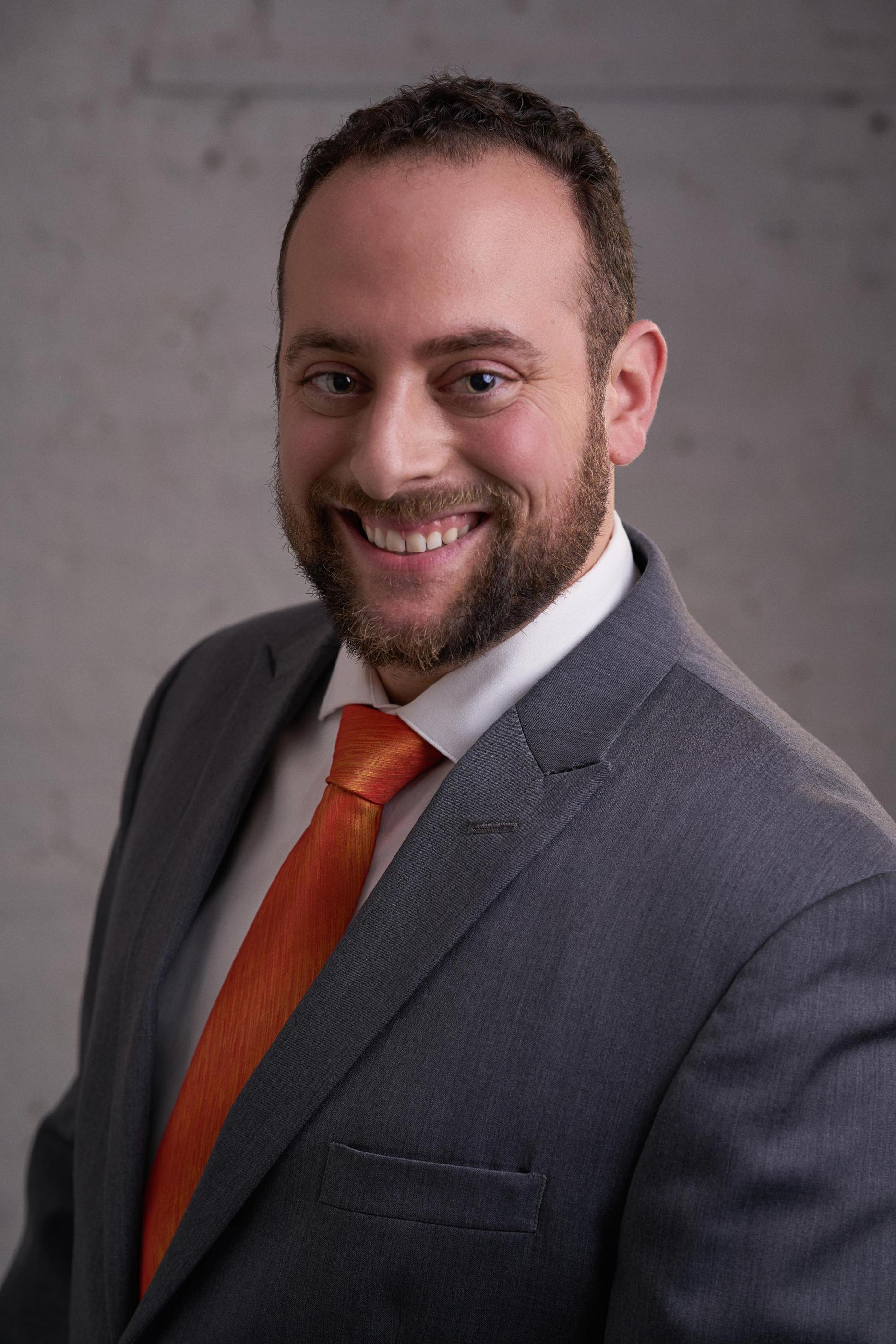 Man in a gray suit and orange necktie
